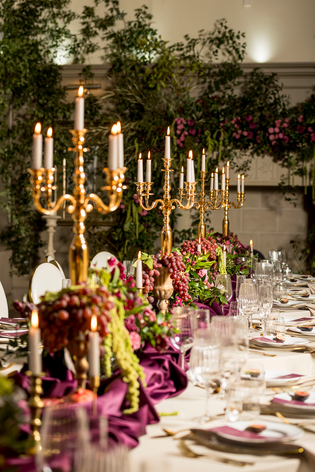 Long reception table with rich flowers and candlelight at Ellingham Hall