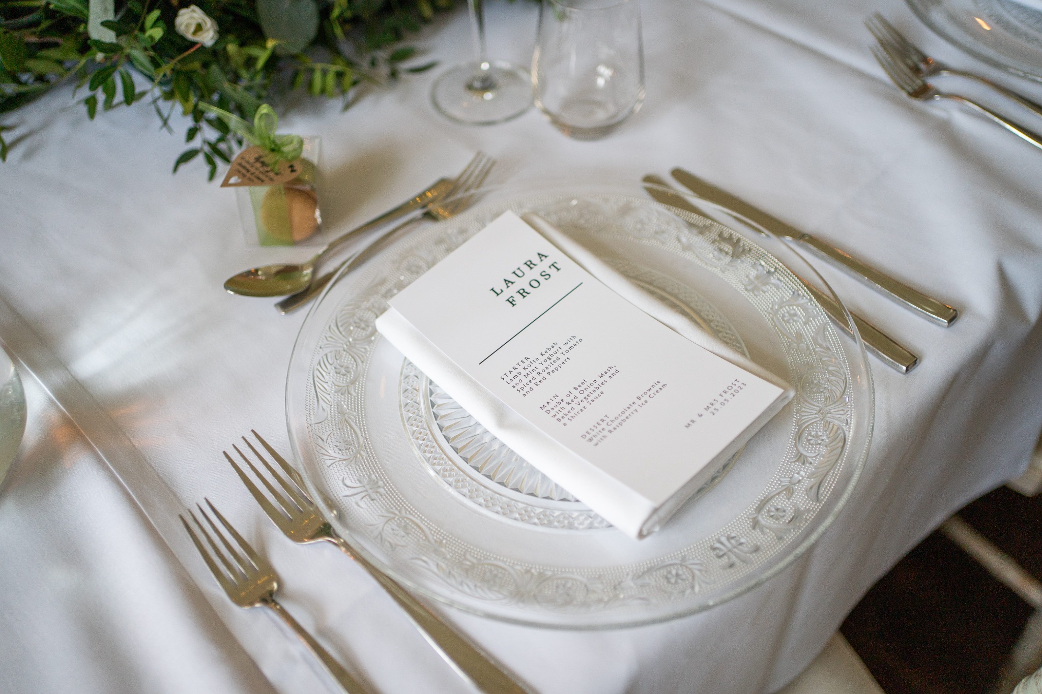 Personalised wedding menu on a glass plate at a reception table