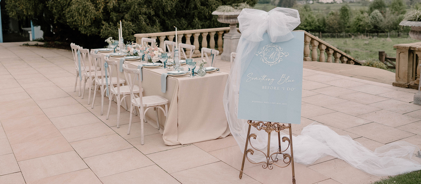 Pale blue wedding sign beside an outdoor wedding table