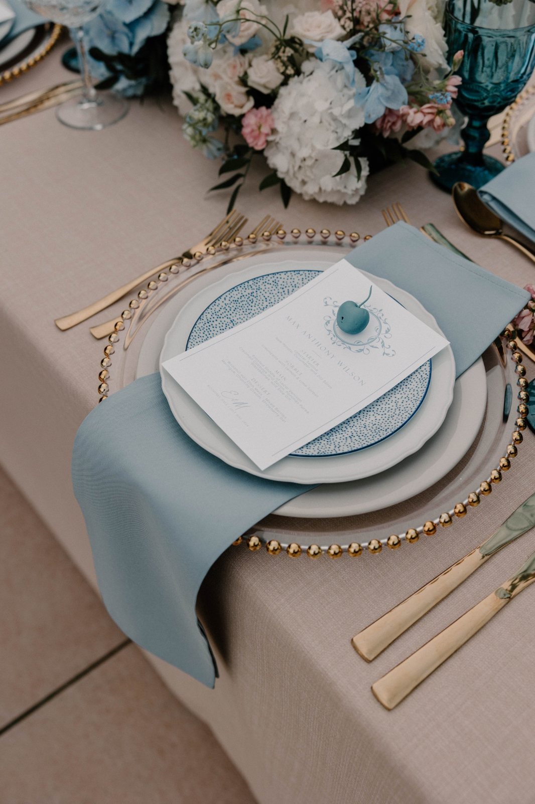 Wedding place setting with pale blue menu, napkin and floral centrepiece