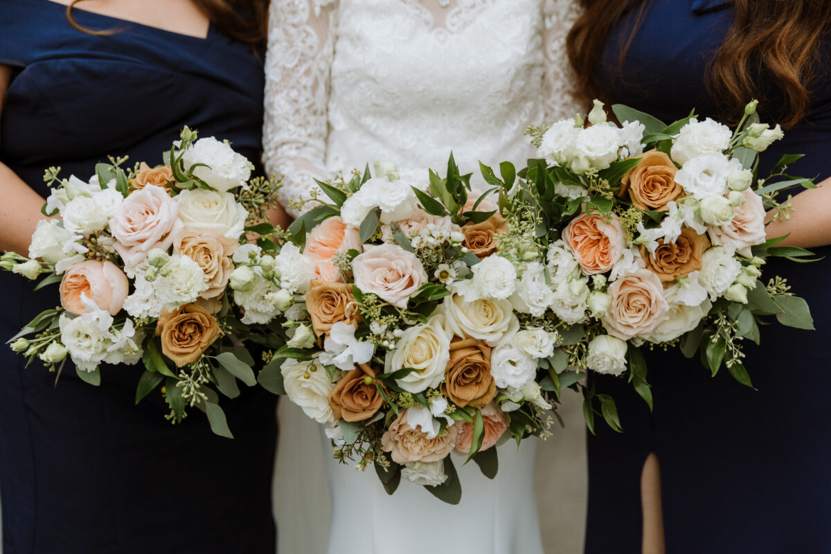Bridal party carrying bouquets in warm neutral tones