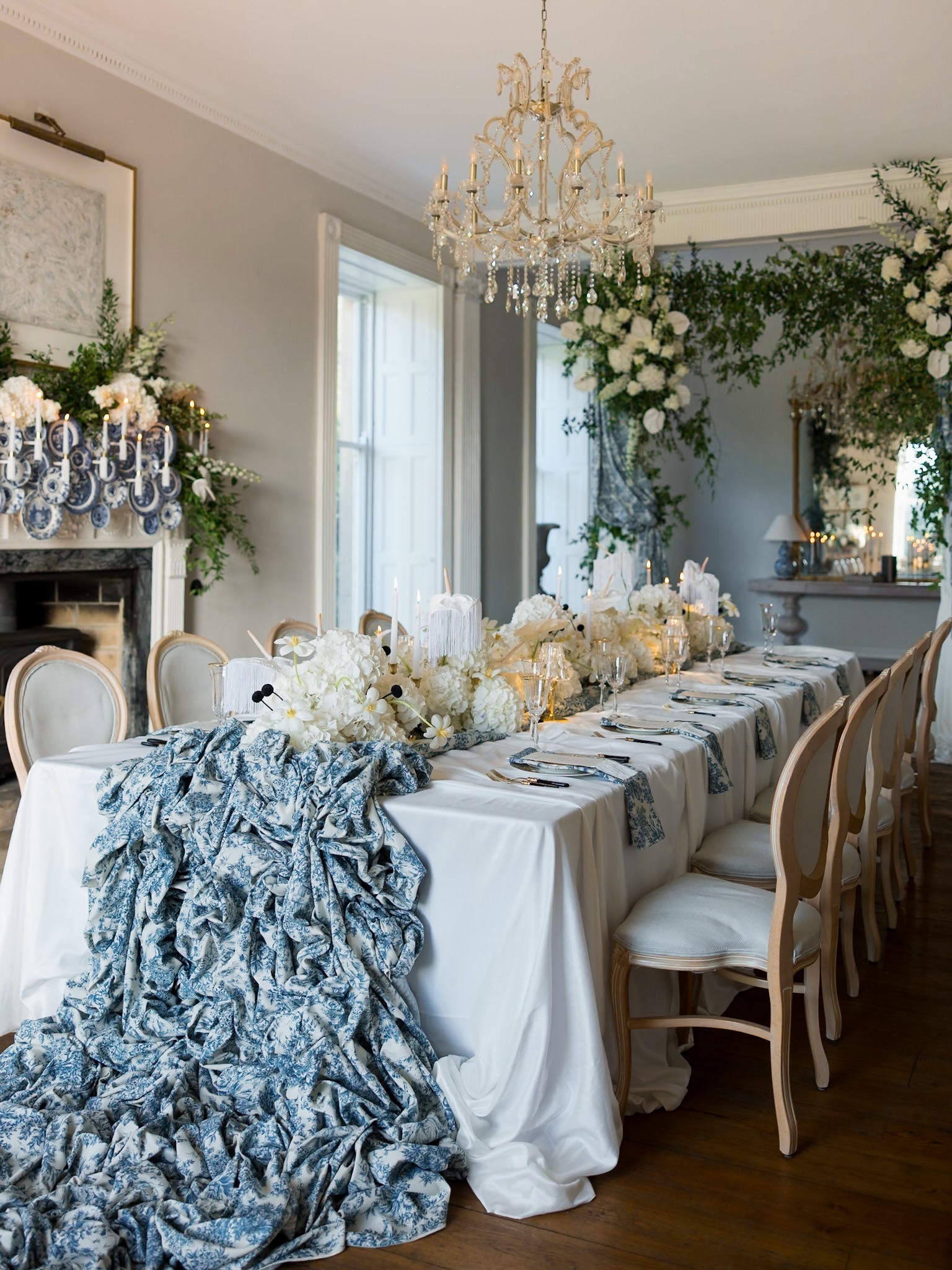 White flowers and candlelight along a reception table with blue patterned fabric