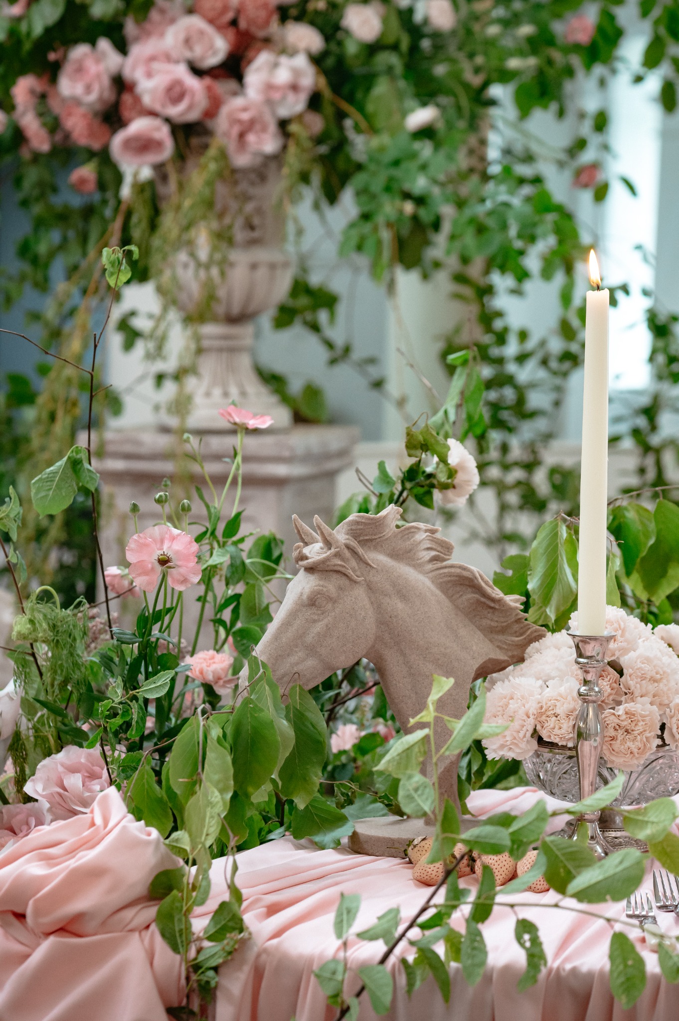 Pink flowers, trailing foliage and a sculptural horse detail on the reception table