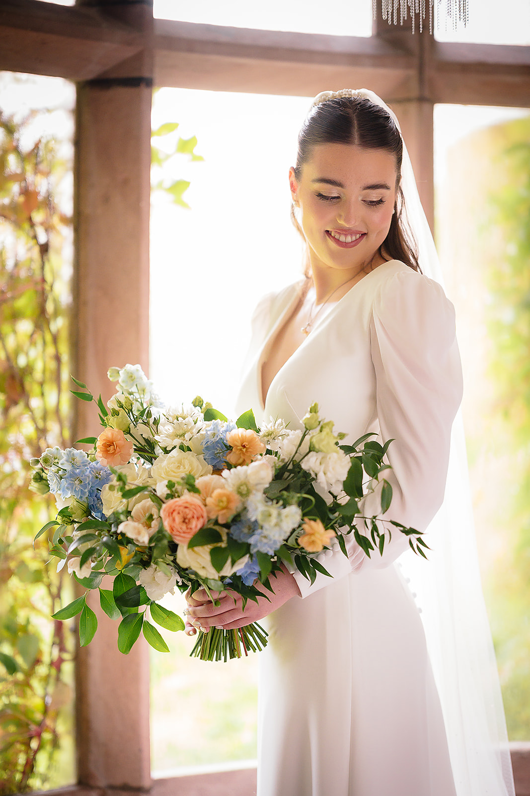 Dani holding a bouquet of peach, blue and white flowers
