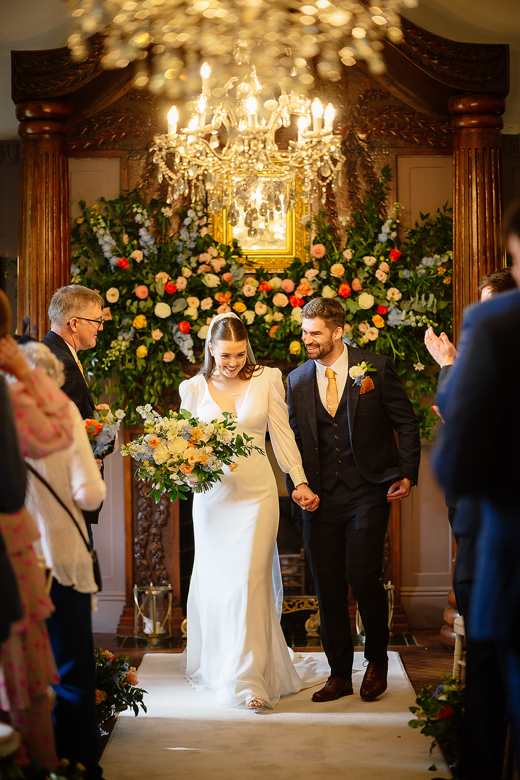 Dani and Callum walking through their flower-filled ceremony