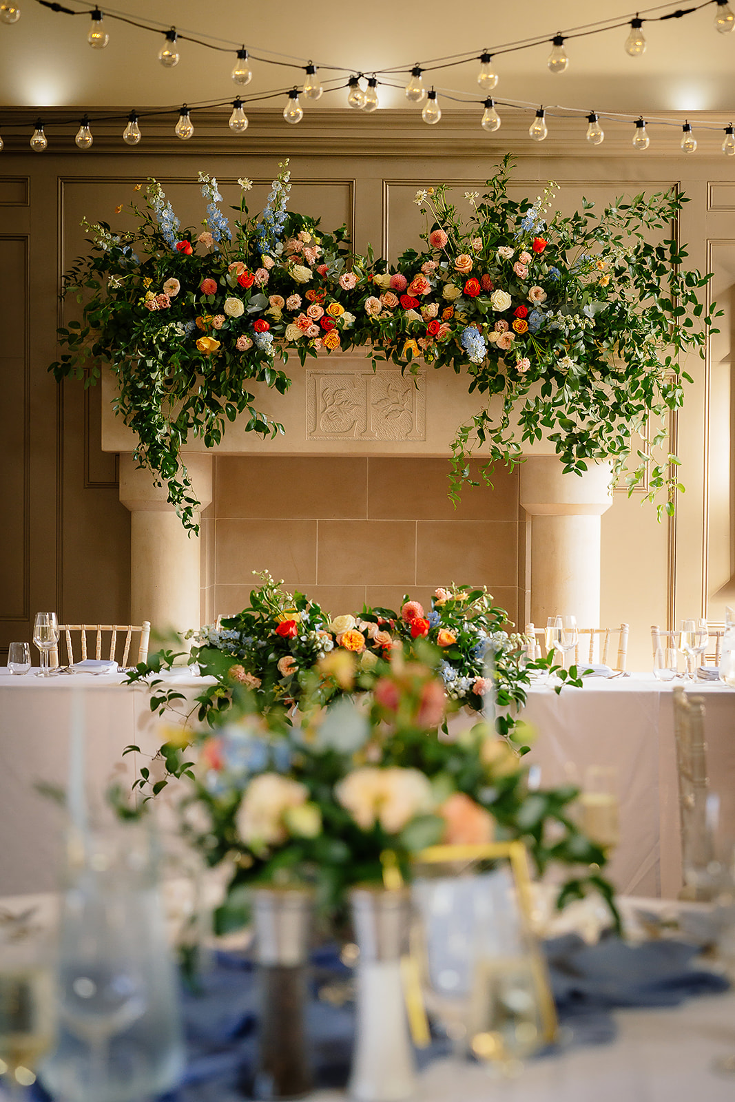 Colourful flowers across the fireplace and wedding table at Ellingham Hall