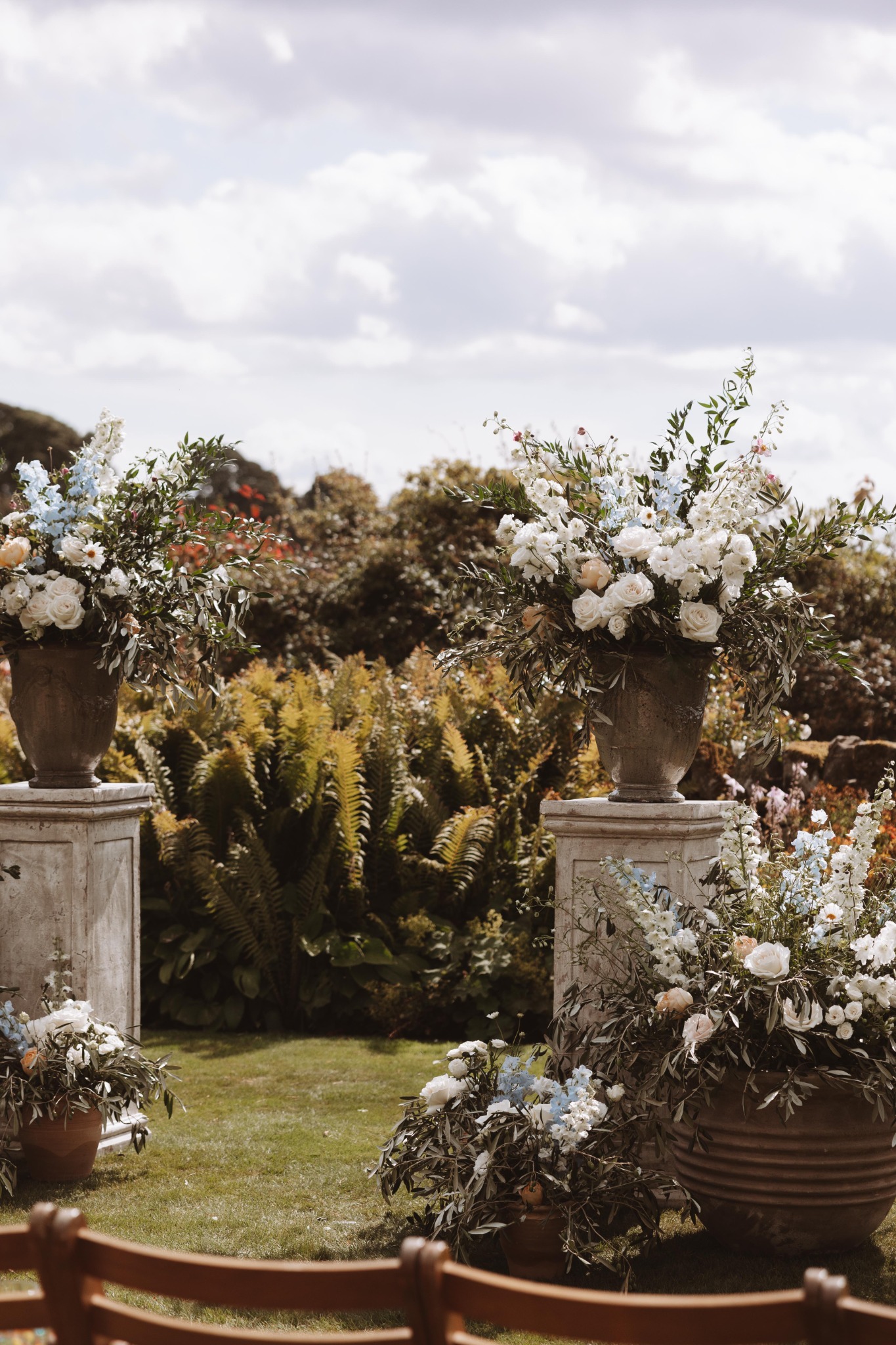 Flower-filled stone urns framing the outdoor ceremony at Halton Grove